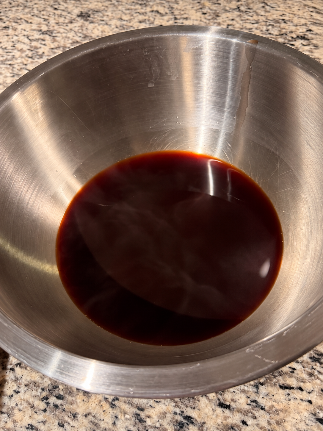 A stainless-steel bowl of deep reddish-brown dye made from saved avocado peels and pits