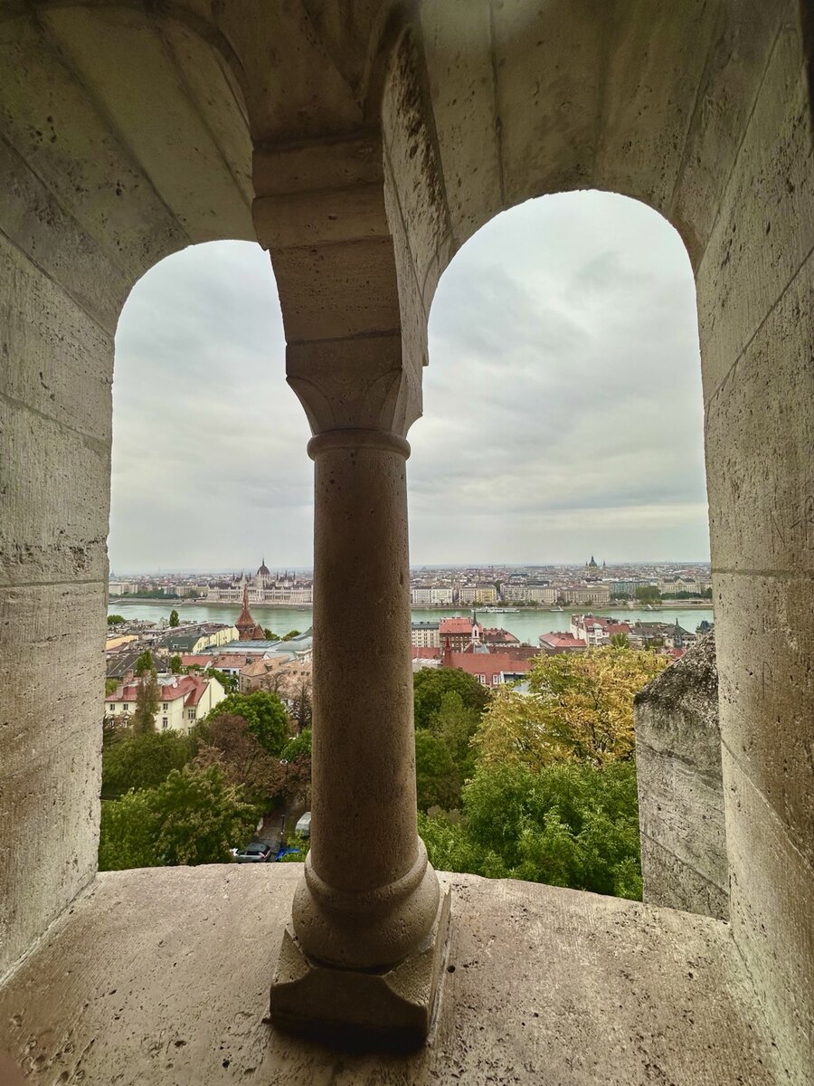 The Danube and Hungarian Parliament seen through the stone arches of Fisherman’s Bastion in Budapest
