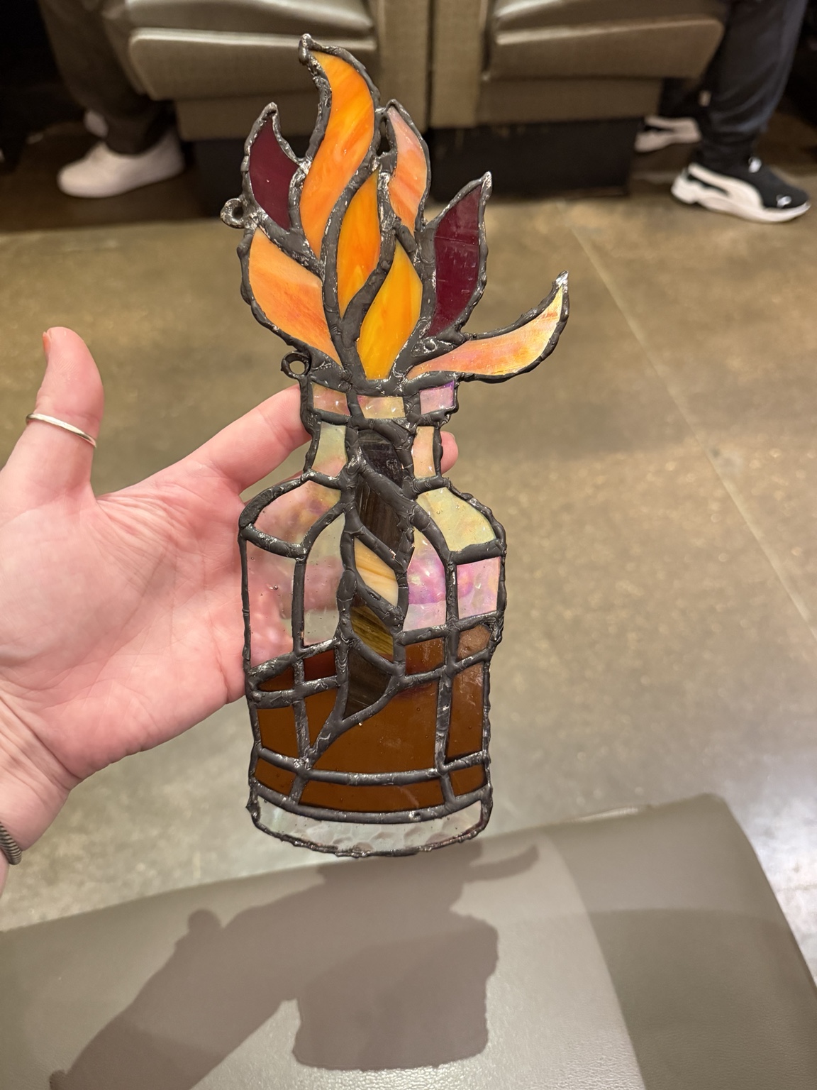 Handheld stained-glass bottle with orange flames, iridescent glass, and dark soldered seams