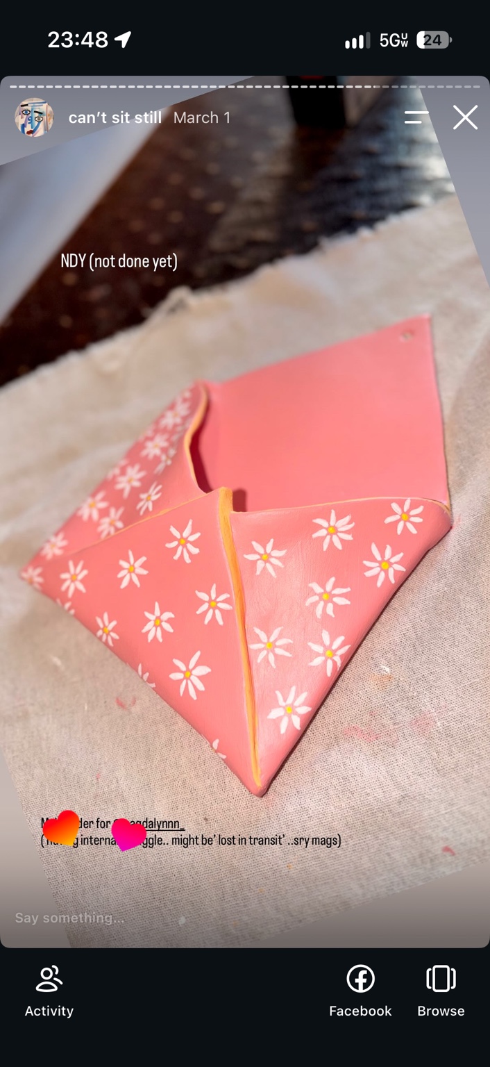 Hand-built pink air-dry-clay mail holder shaped like an open envelope, decorated with white daisies and gold edges, shown in progress