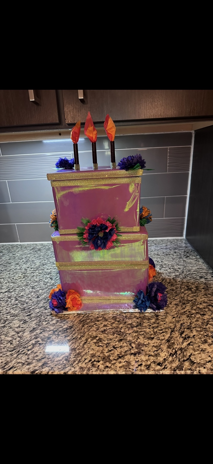Several birthday presents disguised as a pink iridescent tiered cake with gold trim, paper flowers, and pretend candles