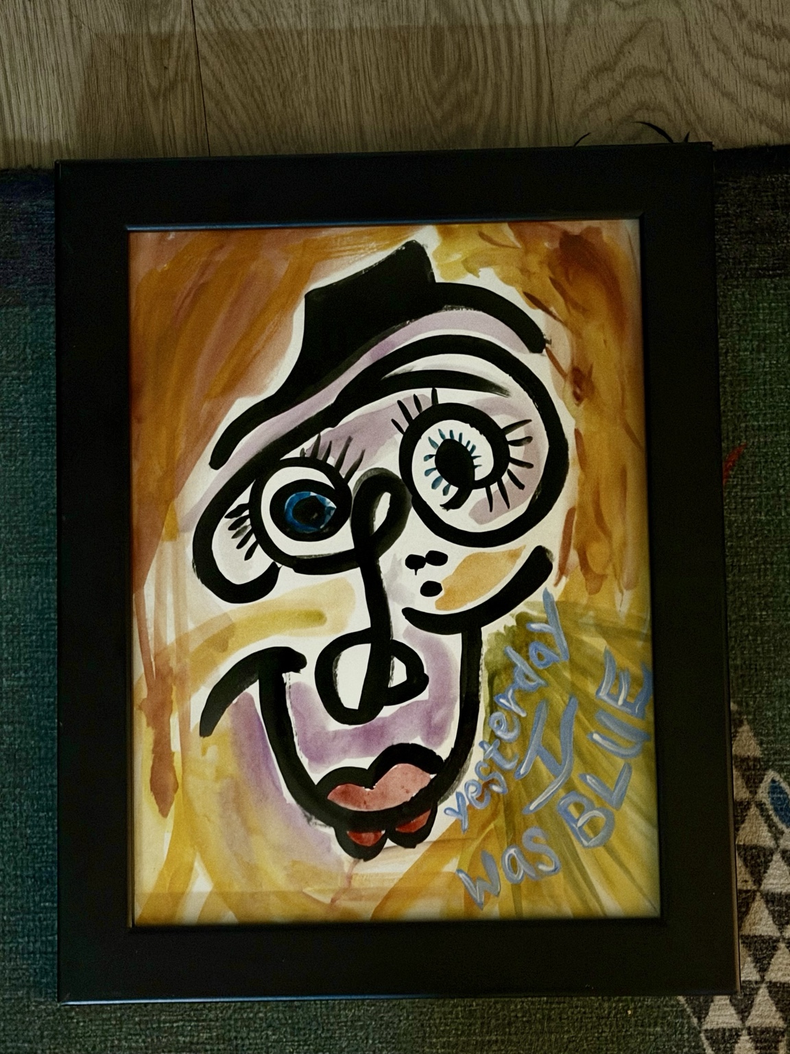 Framed watercolor of a smiling abstract face against yellow and orange, with the words yesterday I was blue